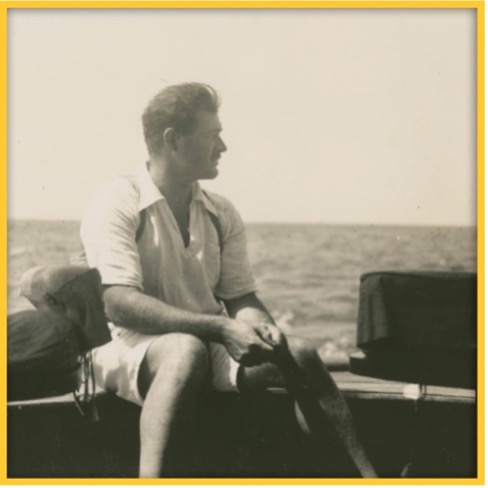 Black and white photo of Ernest Hemingway sitting on a boat