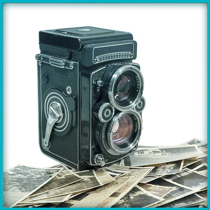 Photo of an old wind-up camera surrounded by old photographs