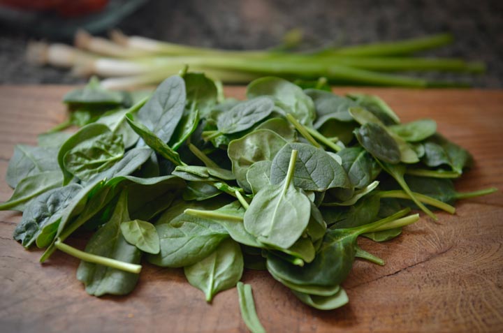 Photo of spinach leaves on a wooden cutting board