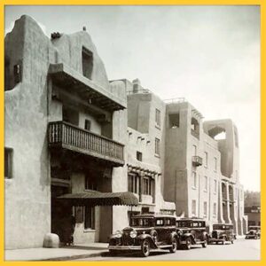 Black and white photo of La Fonda hotel in Santa Fe from the 1930s, a row of cars parked in front