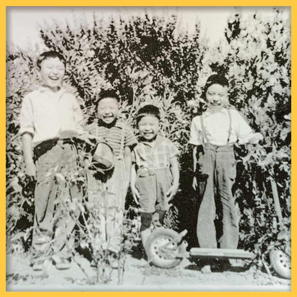 Photo of 4 young boys in 1939 posing and laughing. One of them is holding a scooter