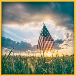 American flag in a grassy field at sunset