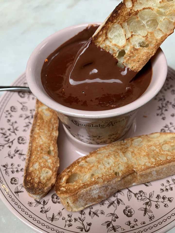 A photo of bread being dipped into a bowl of melted chocolate