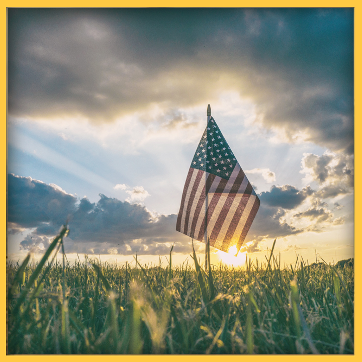 American flag in a grassy field at sunset