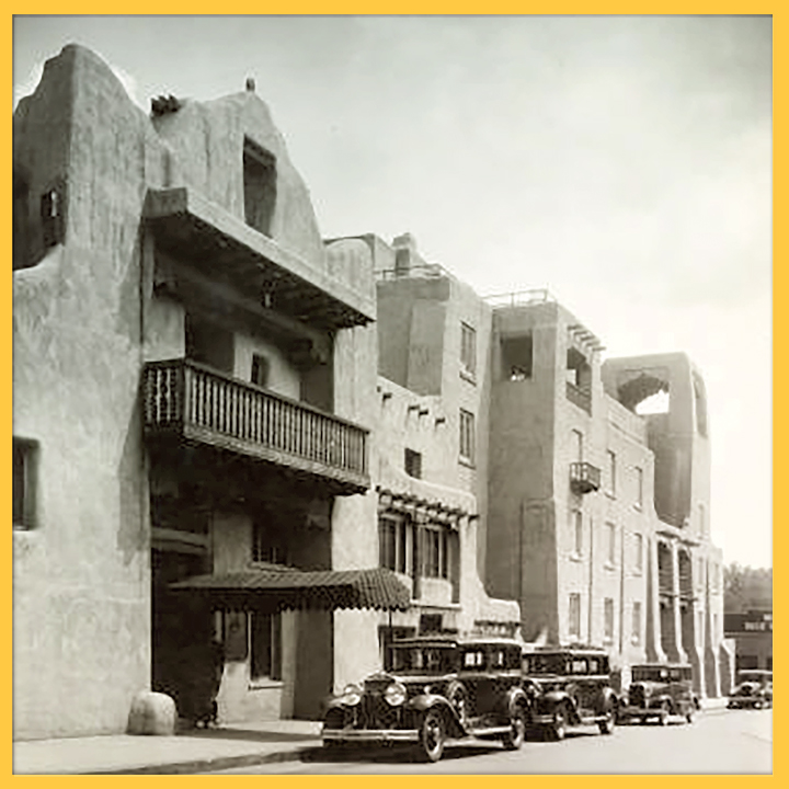 Black and white photo of La Fonda hotel in Santa Fe from the 1930s, a row of cars parked in front