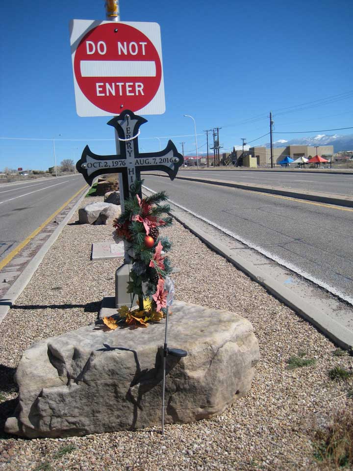 Photo of a road memorial, a crucifix under a "DO NOT ENTER" road sign