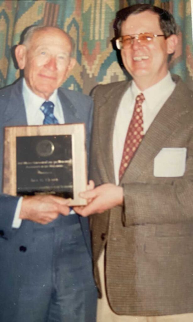 Jimmy Miller standing with Dr Clark, who is holding a plaque.