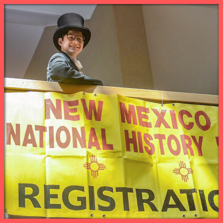 National History Day student dressed in a top hat standing by the registration sign.
