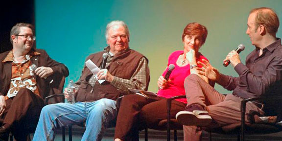 Four people participating in a panel discussion on stage.