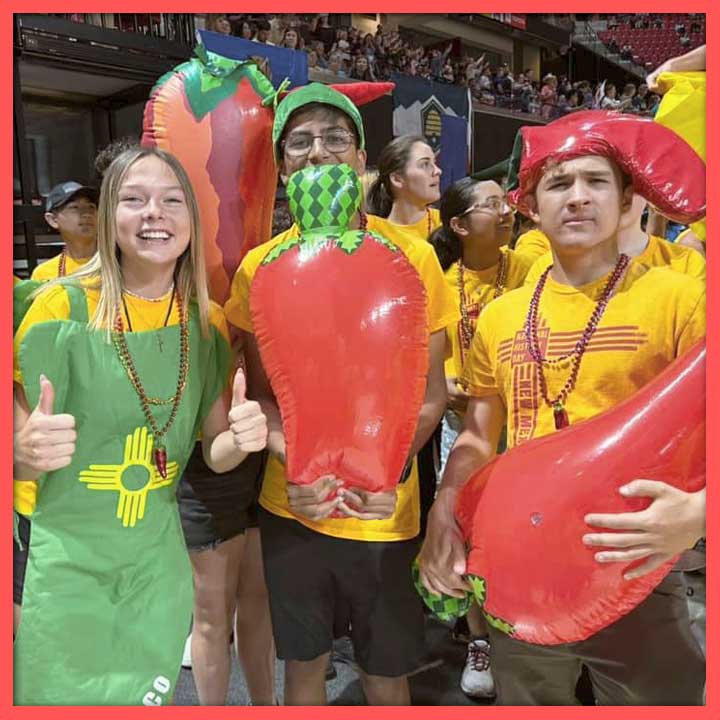 Three students at the NHD Nationals awards ceremony, dressed as and holding inflatable chile peppers.