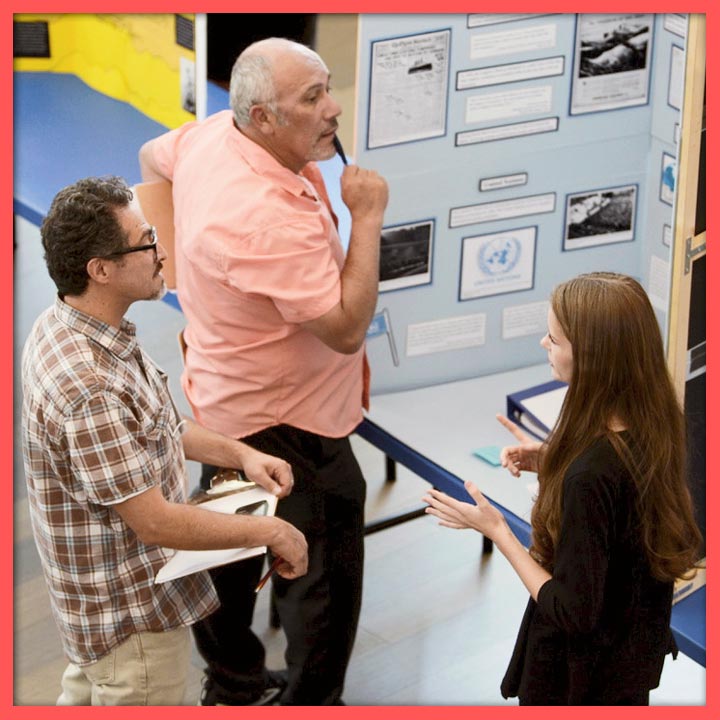 Two NHD judges listen to a student explain her project